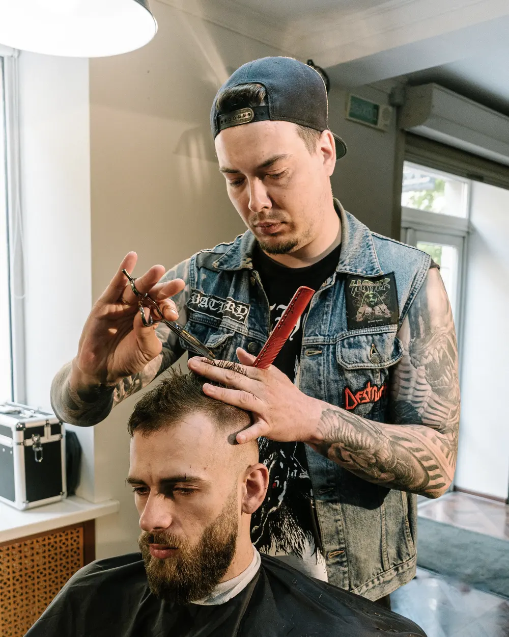 Barber z tatuażami strzyże klienta w zakładzie